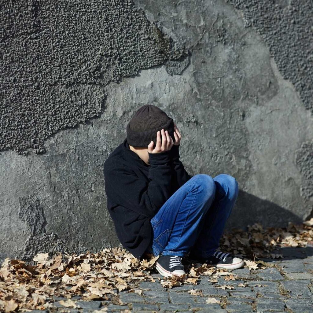 A Orphaned Child leaning his back against rocking wall and crying